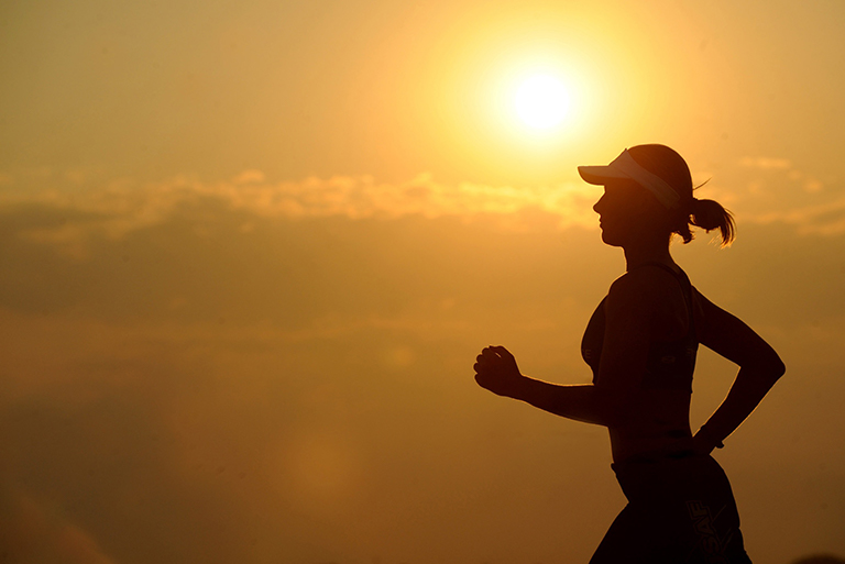 Woman jogging in front of a setting sun; WIC nutrition and health assessment